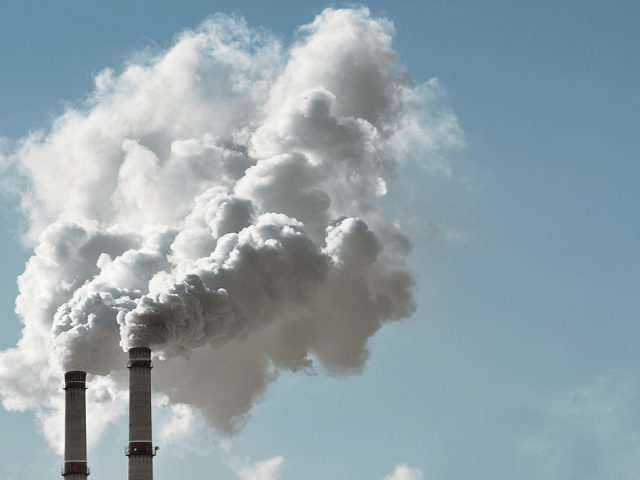 Industrieschornsteine die Rauch ausstpßen mit Himmel im Hintergrund